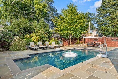 Elegant backyard swimming pool surrounded by landscaping and outdoor seating area.