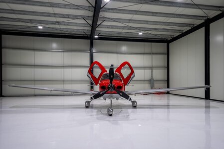 Modern experimental airplane inside a spacious hangar.