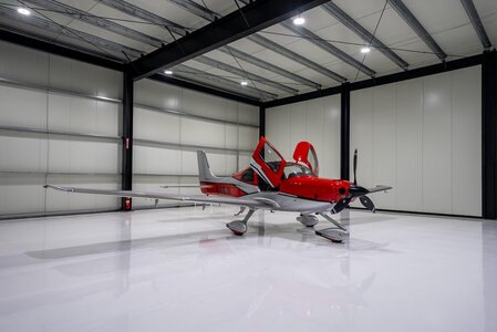 High-tech aircraft inside a sleek, spacious hangar with bright lighting.