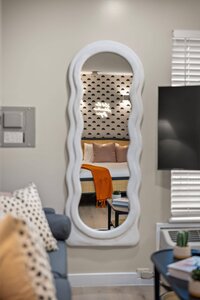 Stylish, cozy bedroom with trendy decor, featured through a decorative mirror in a contemporary home.