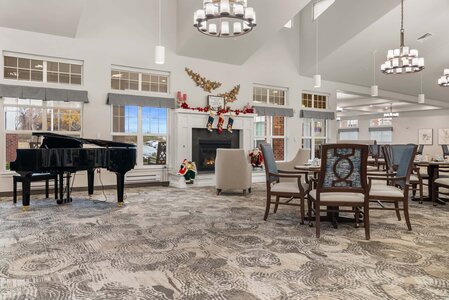 Bright, spacious room featuring festive holiday decor, a glossy black grand piano, and a modern fireplace.