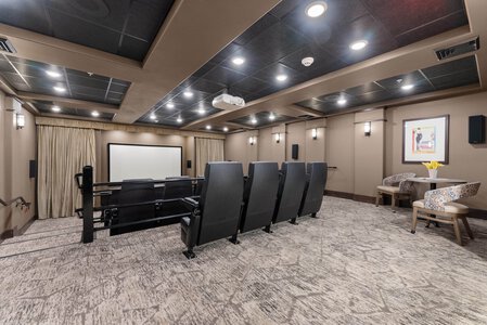 Home theater room with plush chairs, large screen, and surround sound for immersive entertainment.