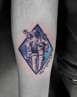 Tatuajes 11 Diseño con fondo azul estrellado que representa un astronauta flotando en el espacio, encapsulado en una forma geométrica con estilo ilustrado.