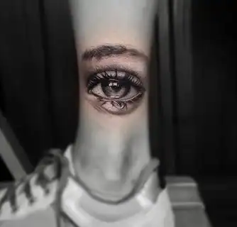 Tatuajes 24 Un tatuaje hiperrealista de un ojo humano, con detalles minuciosos en las pestañas y reflejos en la pupila, capturando una mirada profunda y expresiva.