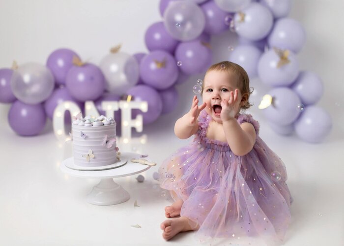 Cake smash session for one year old birthday girl with purple and butterfly theme in Edmonton