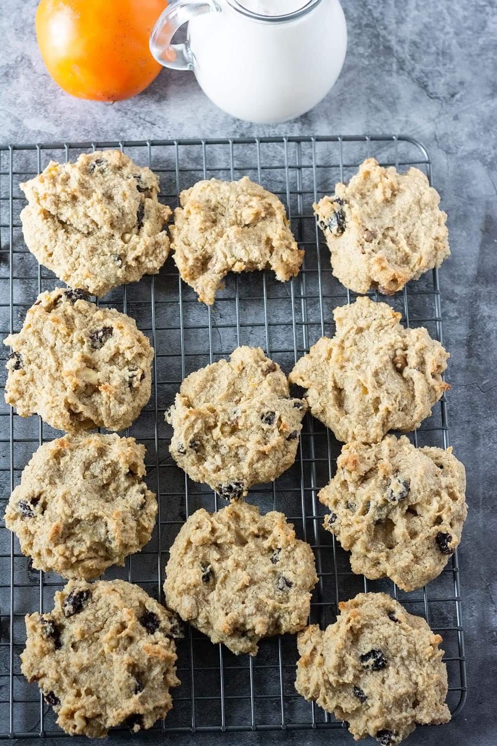 Vegan persimmon cookies overlay cookies on a baking rack with milk in a glass jug and a persimmon in the background