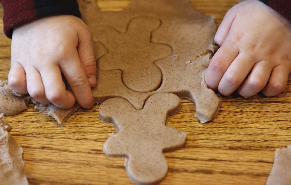Picture of a child cutting out gingerbread shapes from play dough in a pretend bakery.