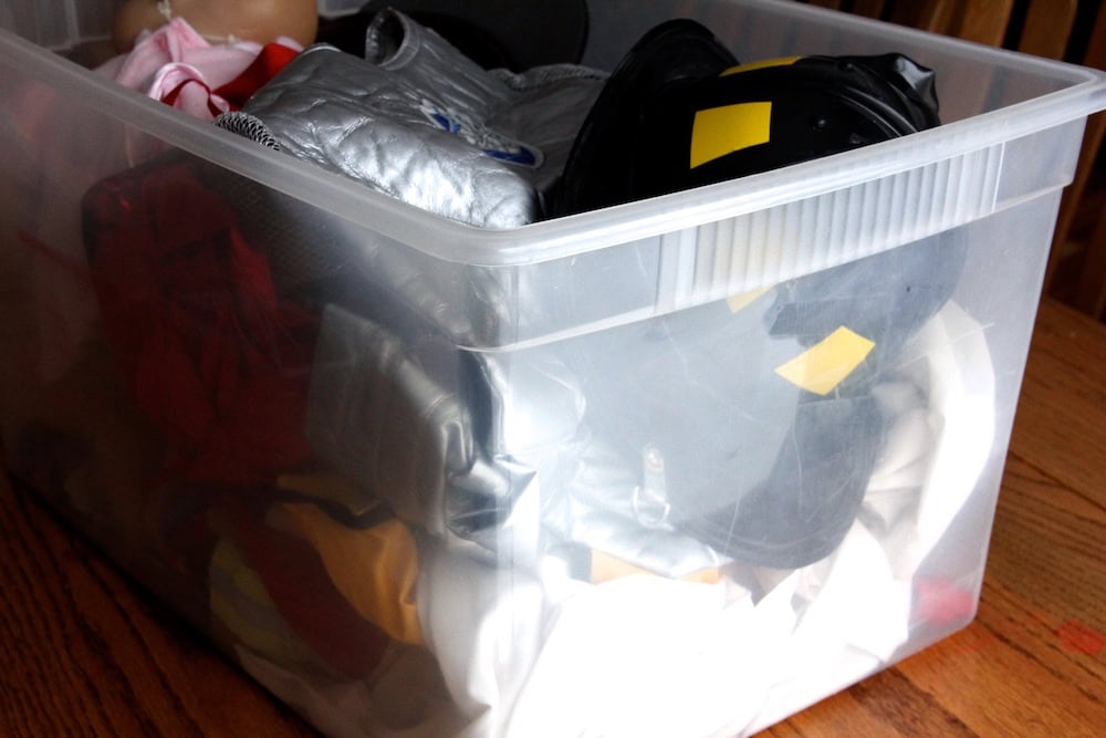 A photo with a large clear plastic bin full of children's dress-up clothes