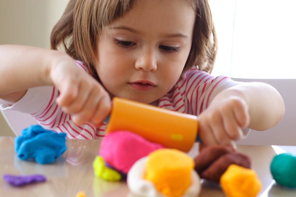 Photo of young girl playing with play dough.