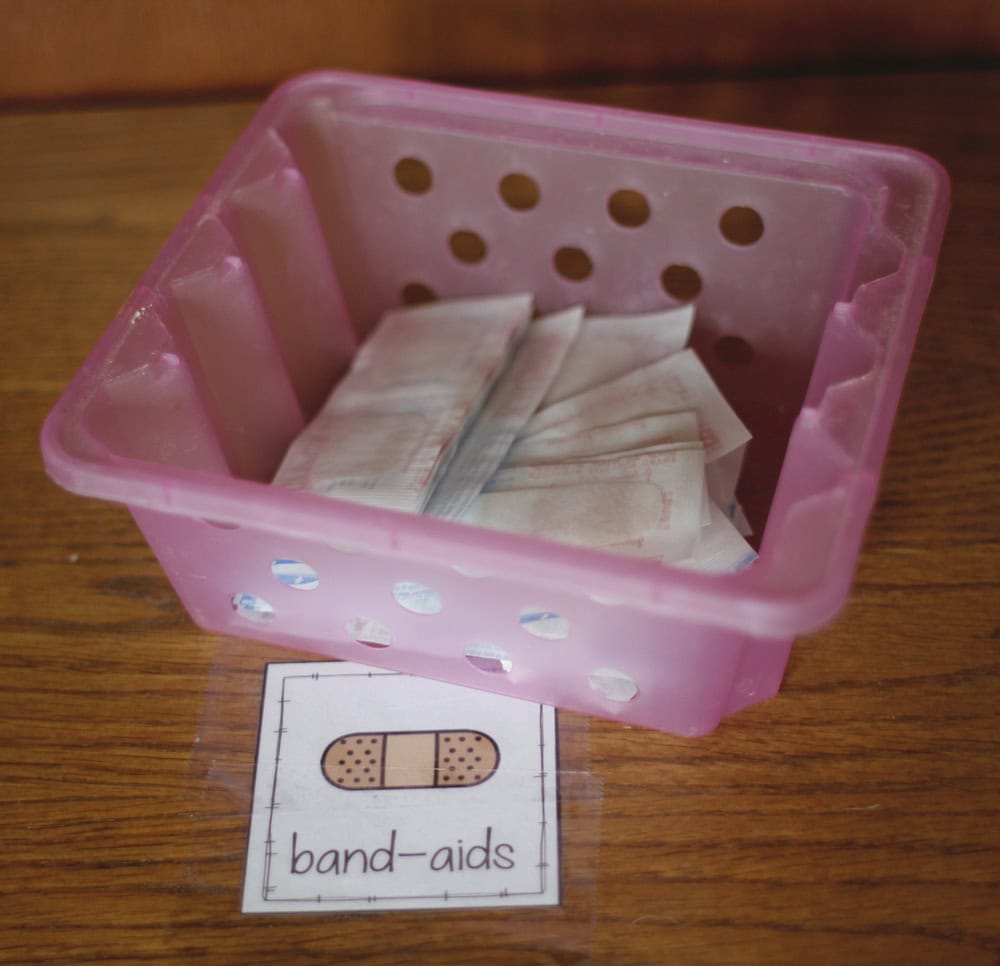 Photo of a small box containing band-aids on a shelf with a label that says "band-aids" and a drawing of a bandage.