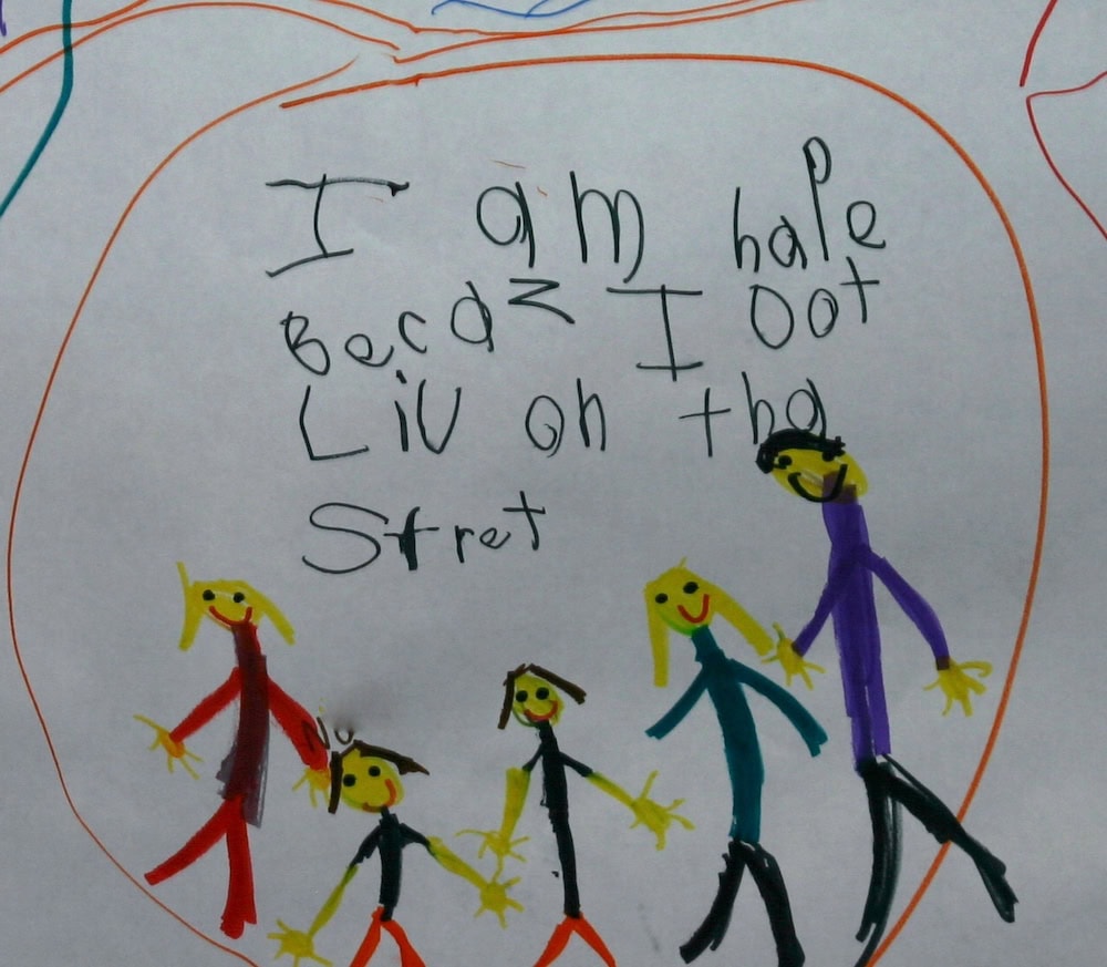 Photo of a student writing samples that says "I am HAPE BECAZ I LIV ON THA STRET" (I am happy because I live on that street.)