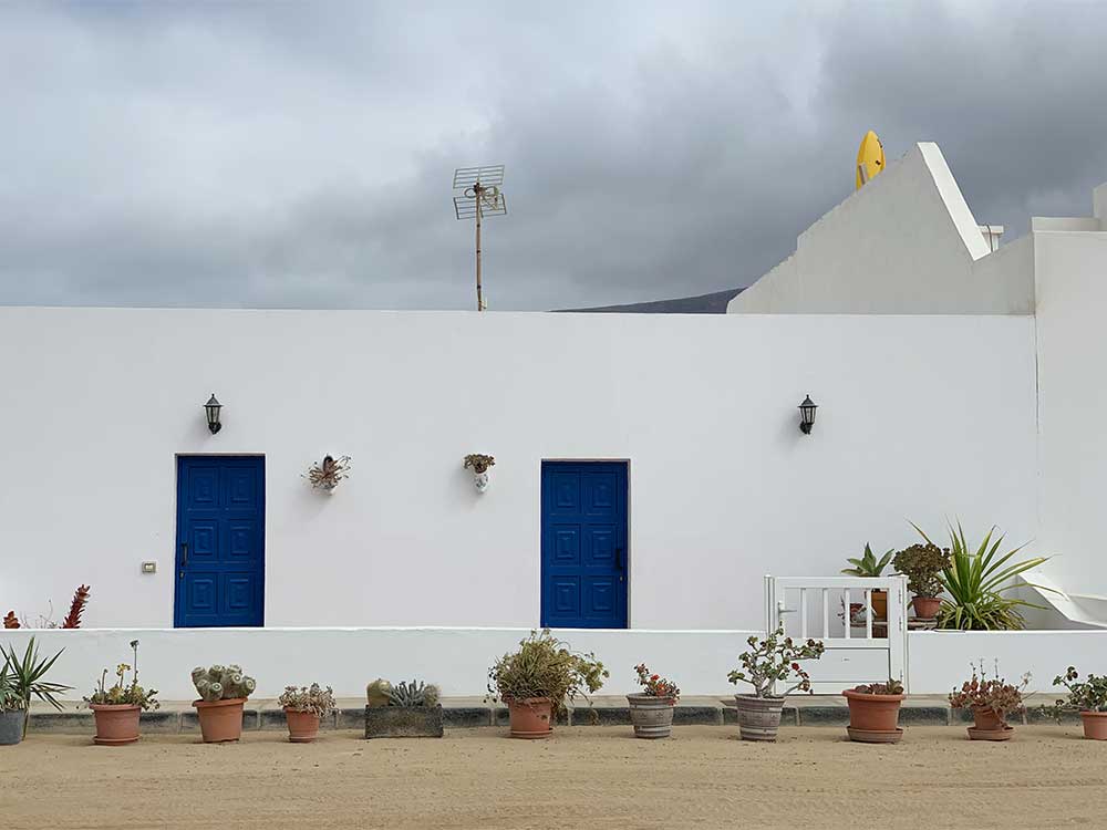 Fachada blanca con ventanas azules en Caleta de Sebo
