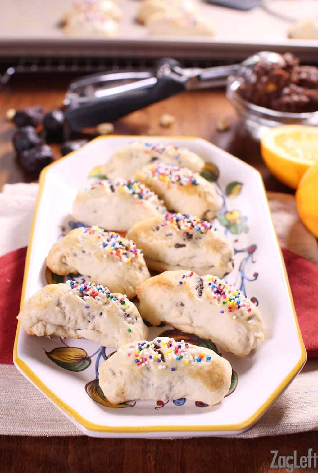 A plate of eight Cuccidati cookies topped with rainbow spinkles