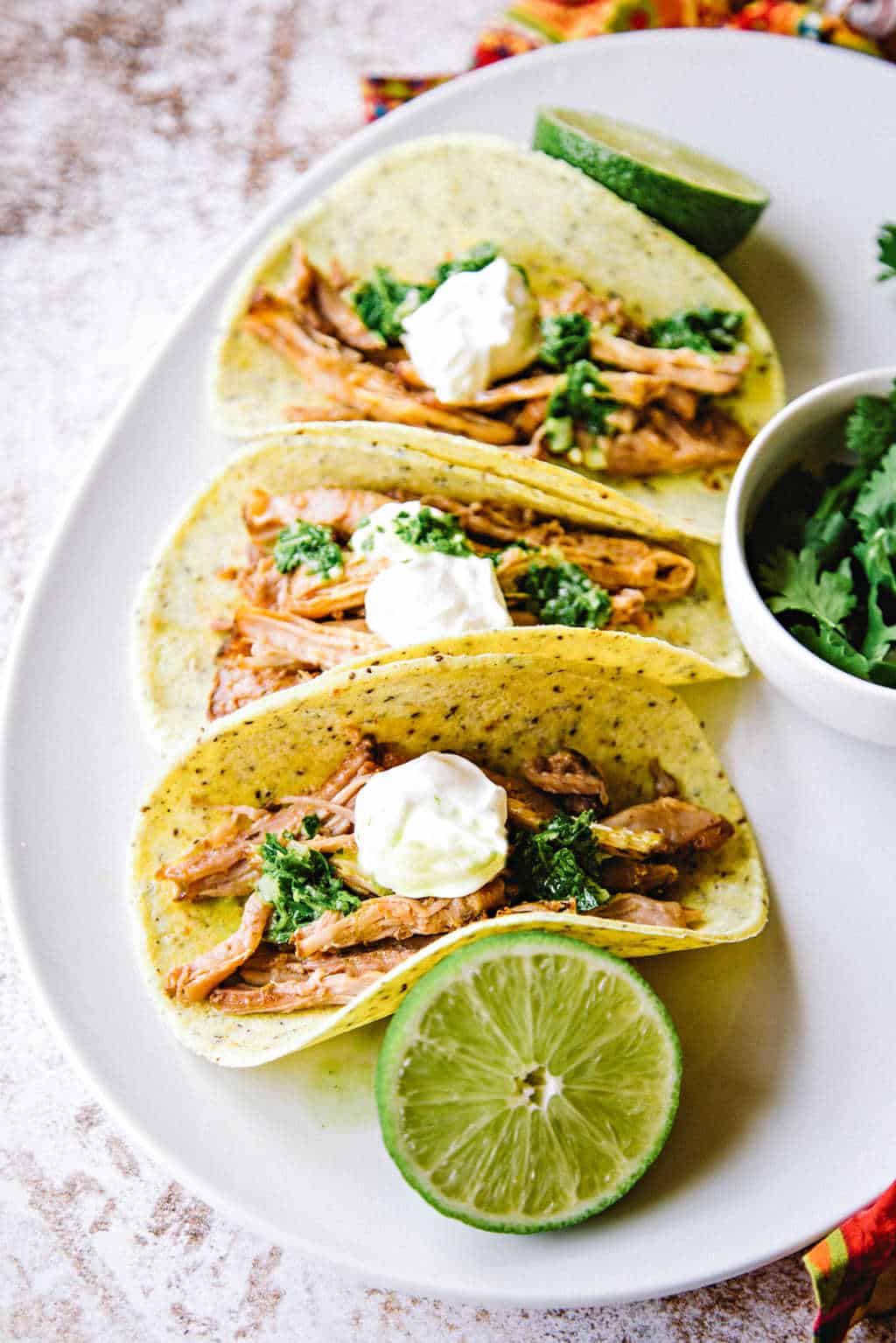 pork carnitas on a white platter with lime slices