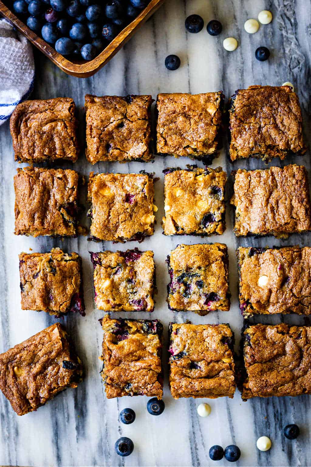 blueberry white chocolate chip cookie bars cut and separated into squares on a marble pastry board