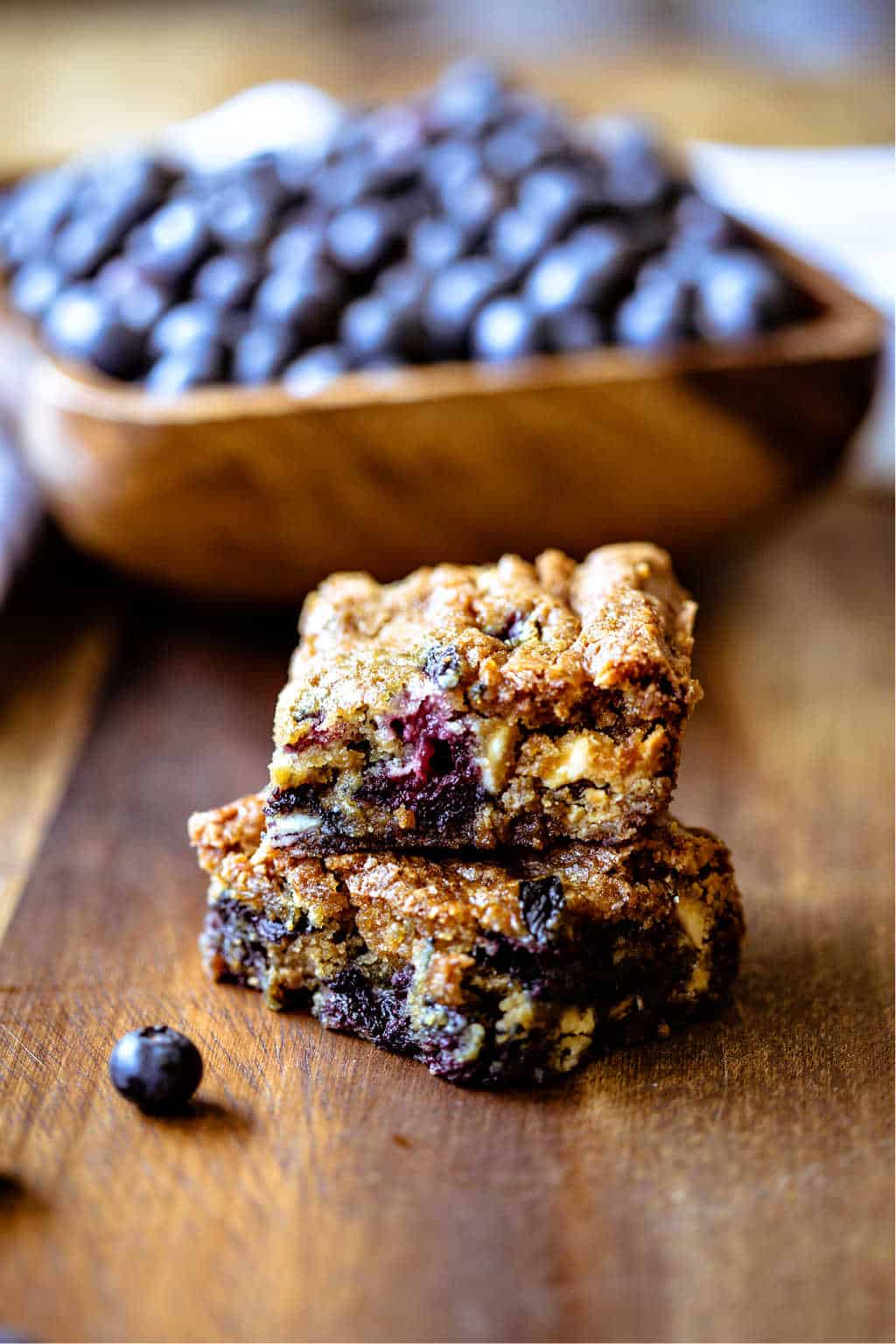 blueberry white chocolate chip cookie bars with a bowl of blueberries in the background
