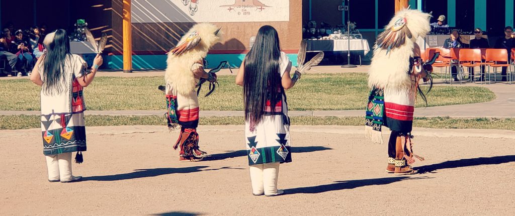 4 people of Zuni dance in traditional regalia in the sandy dance circle at Indian Pueblo Cultural Center one of the best things to do in Albuquerque New Mexico.