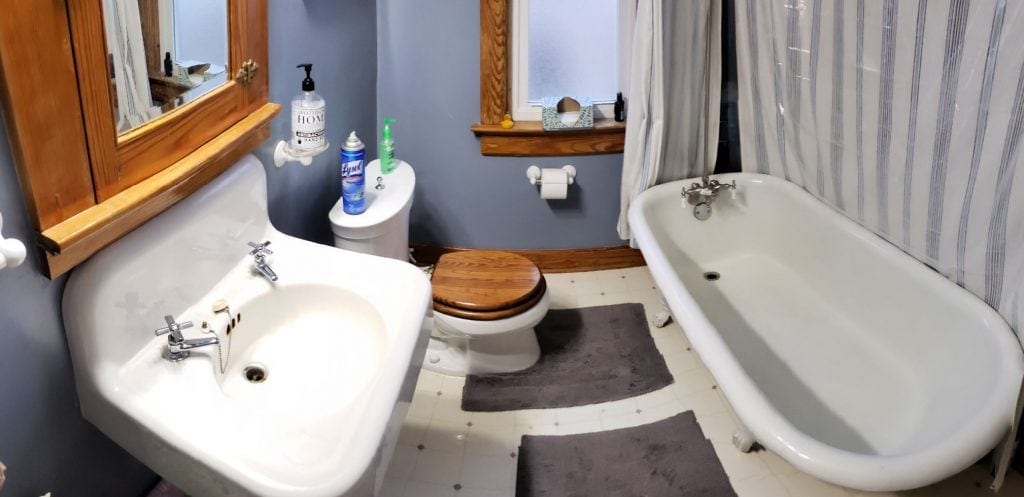 An old fashioned, white wall sink, claw-foot bathtub and toilet in clean bathroom with blue walls in this Elkhart Lakes bed and breakfast