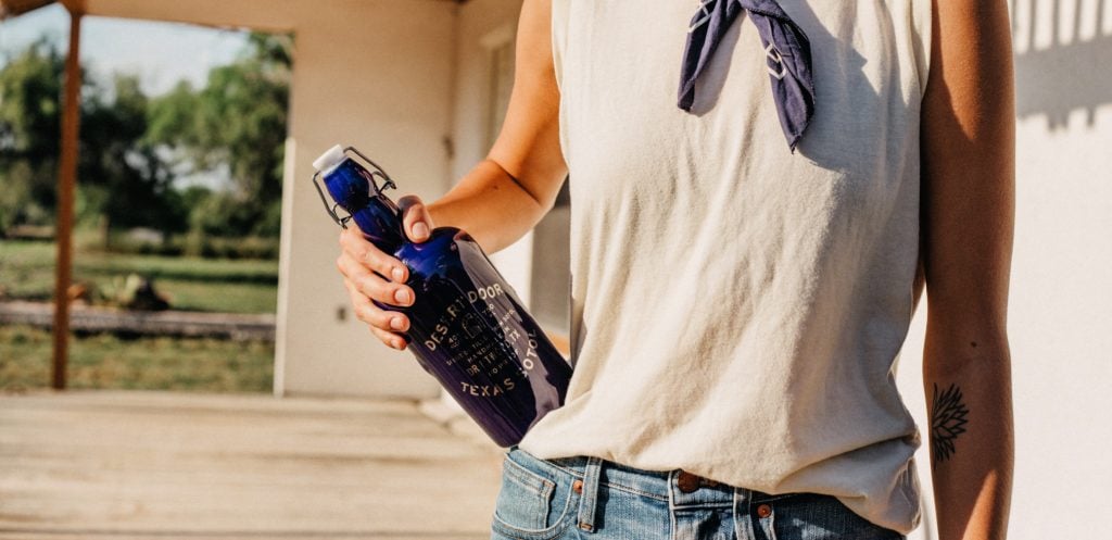 woman with blue bottle of Texas sotol liquor on hip
