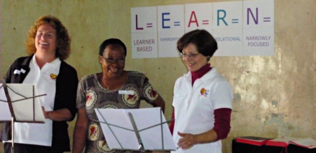 Kidz at Heart instructors stand in front of class of Sunday School teachers with translator