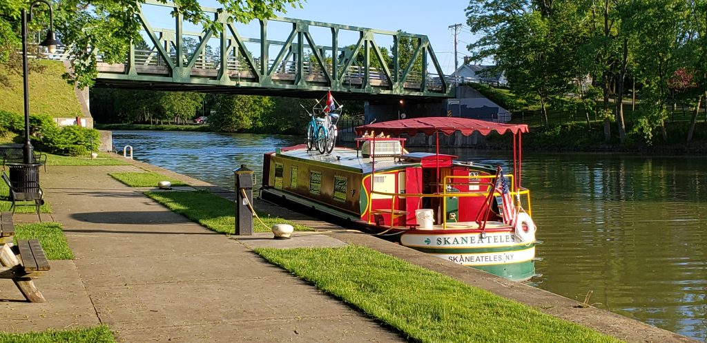 Packet boat in water tied at Pittsford Terminal with historic bridge in background on canal boat holidays United States