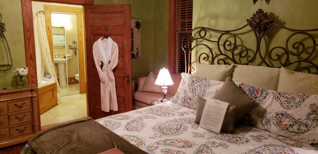 King bed be-decked in colorful bed linens, robe hangs on door at Asheville B&B near Biltmore