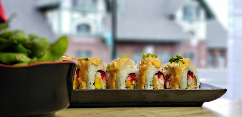 Sushi roll cut on plate at Karma Sushi, best restaurants in Flagstaff - Historic train station is seen through window in background