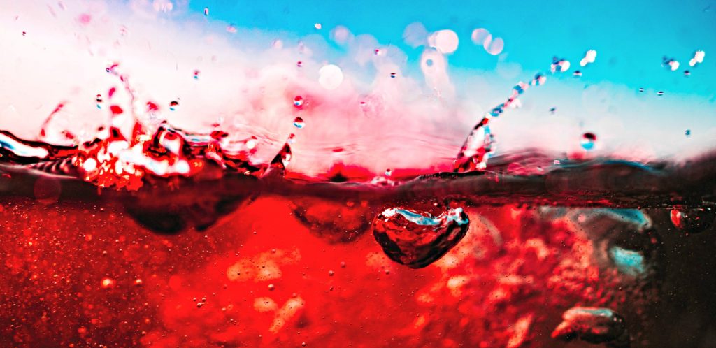 image of close up of red wine showing air being mixed in near rim of glass -depicting just what does a wine aerator do
