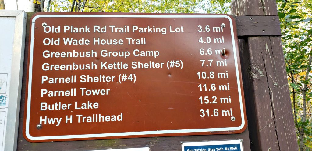 Brown trail sign reading in part: Greenbush Group CAmp: 6.6 mi, Greenbush Kettle shelter (#5) 7.7 miles, Parnell Shelter (#4) 10.8 mi"