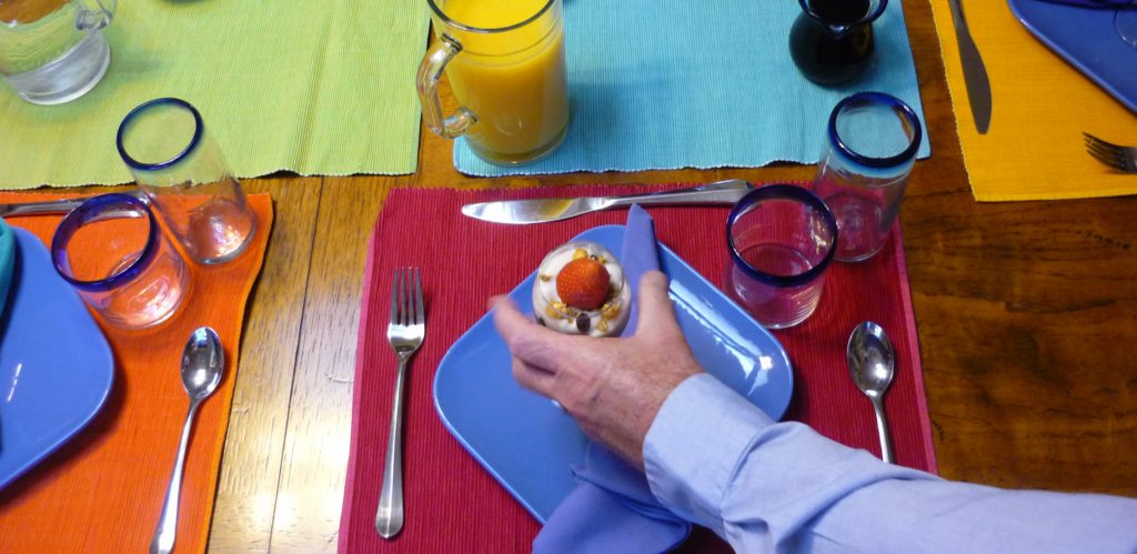 Server's hand reaches onto brightly decorated table with a fruit parfait