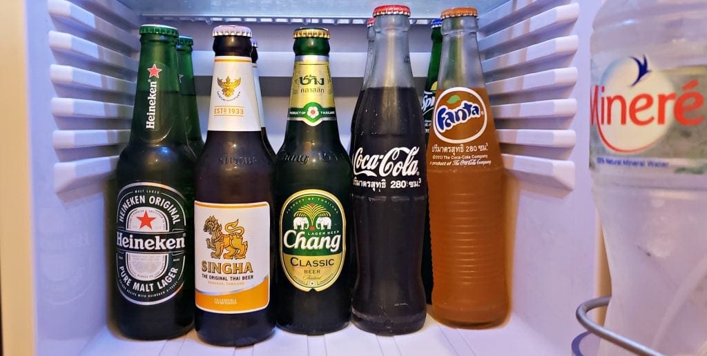 Inside of small refrigerator with Heineken, two local beers, a Thai Coke and Fanta all in glass bottles.