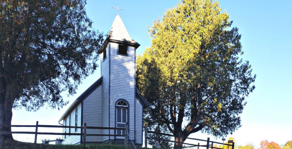 white chapel with tall steeple sits high on hill, one of the Catholic shrines in Wisconsin - not far from Holy Resurrection Monastery