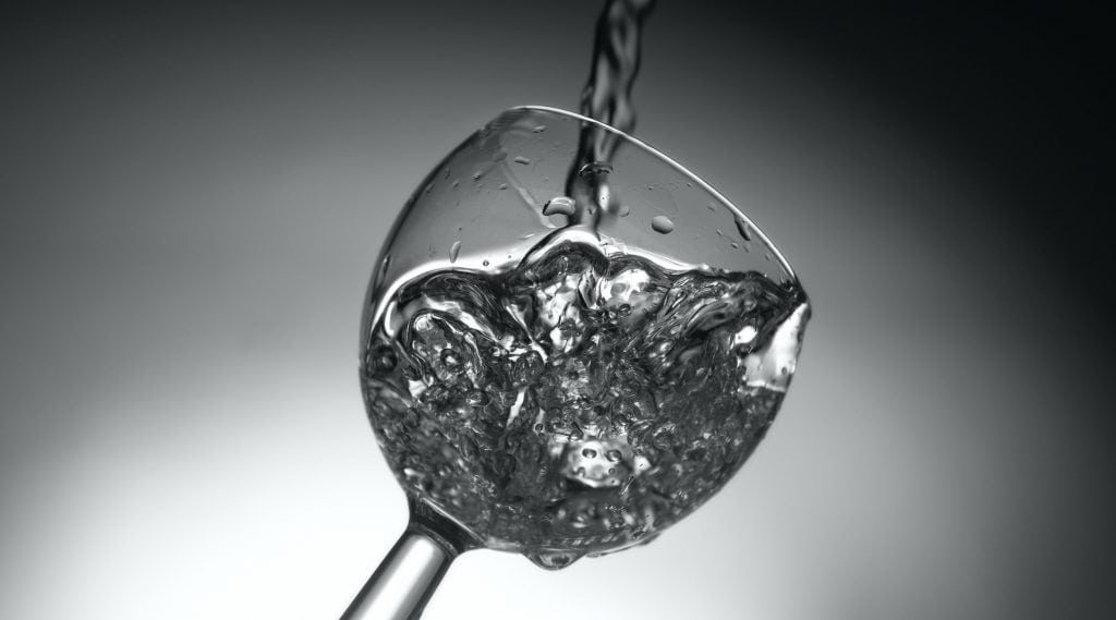 black and white image of wine glass with swirling wine being poured in - demonstrating what does a wine aerator do