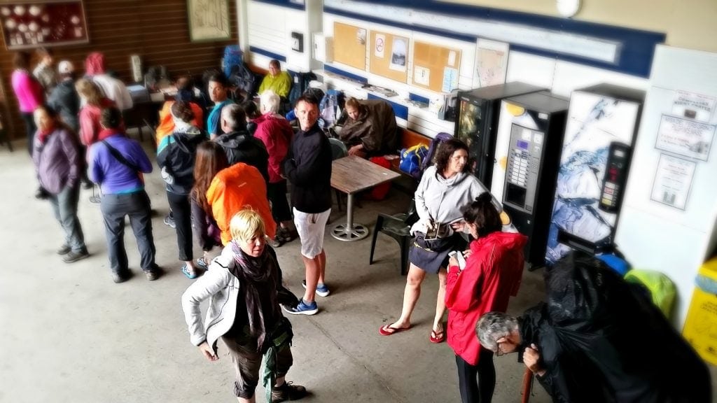 Wet and weary pilgrims stand in line at the registration desk of the Benedictine monastery.