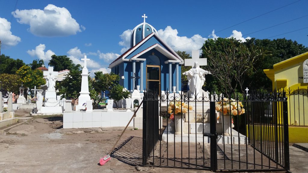 Cemetary with bright blue mausoleum and white crosses.
