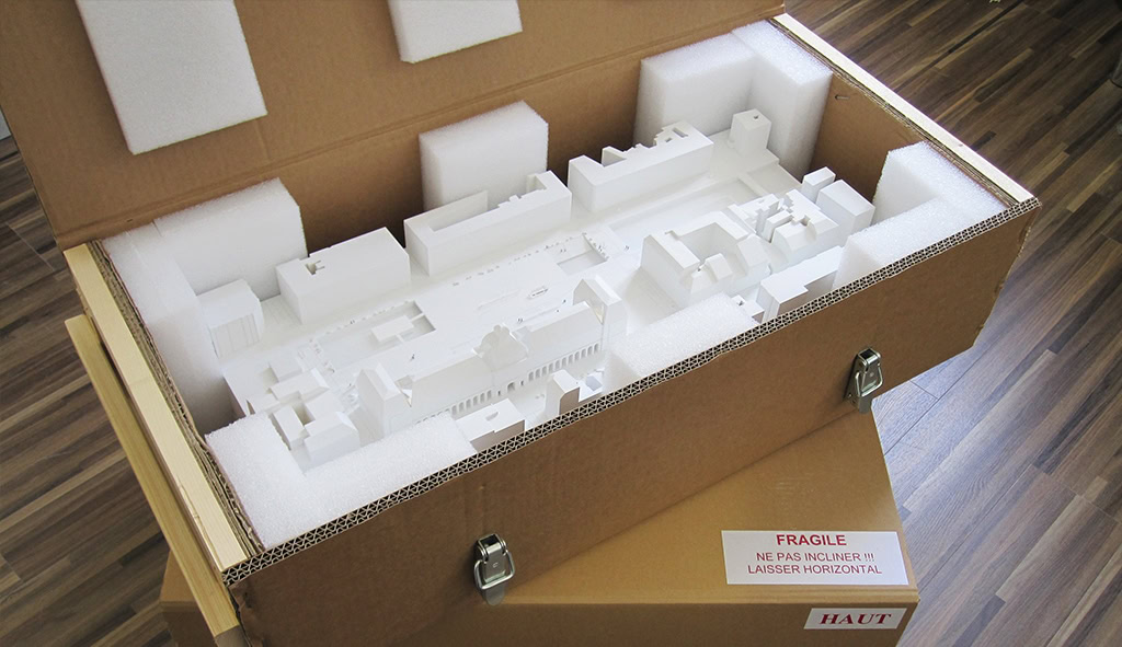 caisse en carton avec un armature bois contenant une maquette d'architecture