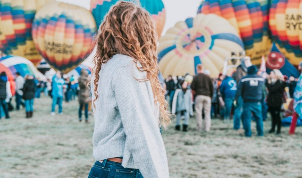 Young woman stands in front of hot air balloons ready to lift off at Albuquerque Balloon Festival - Albuquerque guide