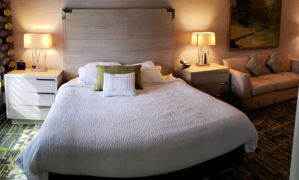 king bed in white comforter with two contemporary side tables/dressers with three drawers each