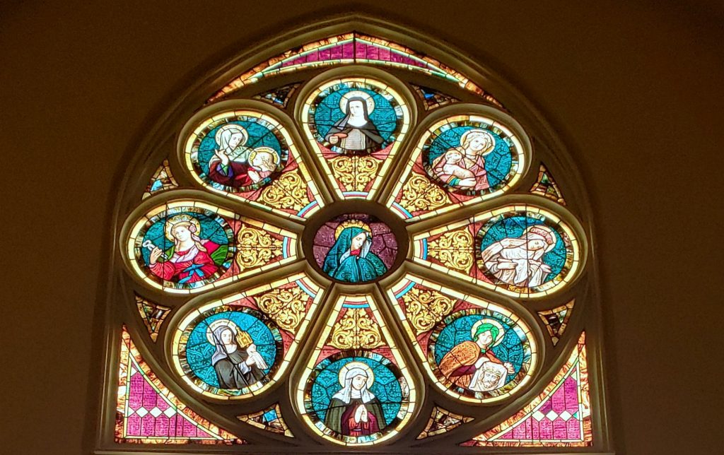 rose window of red and blue glass on the Wisc Way pilgrimage depicting women saints