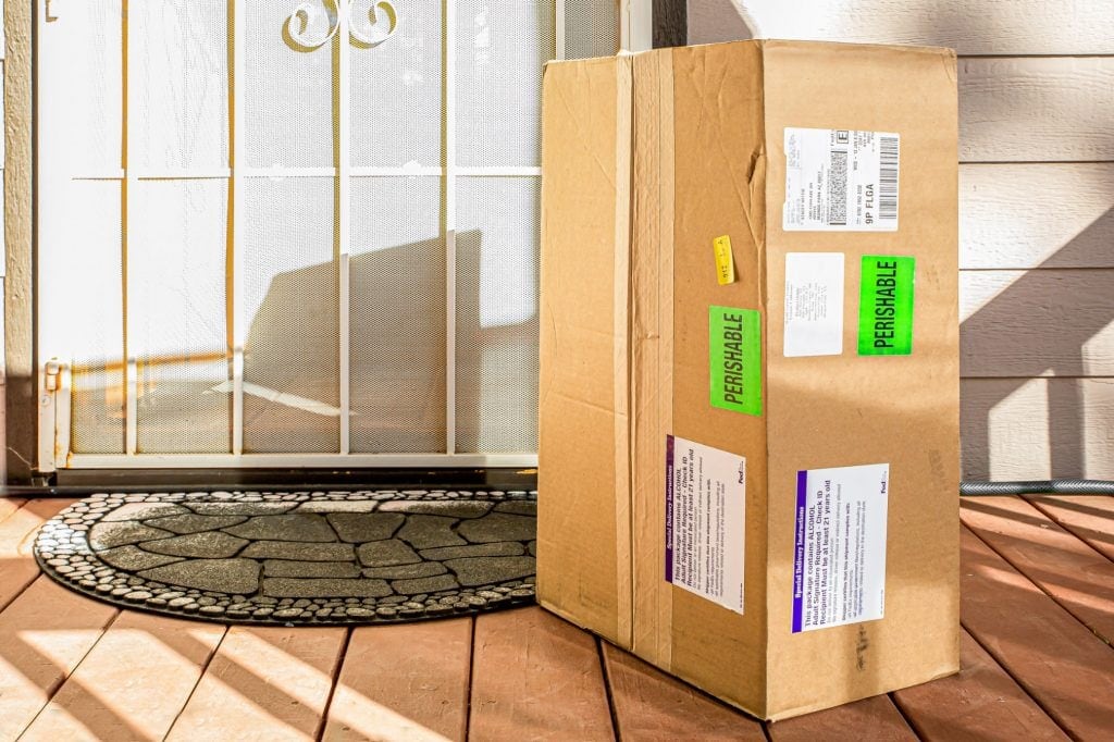 Huge cardboard shipping box sits at door step with colorful labels