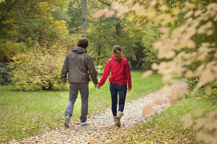 A young couple takes a walk through the park covered with leaves