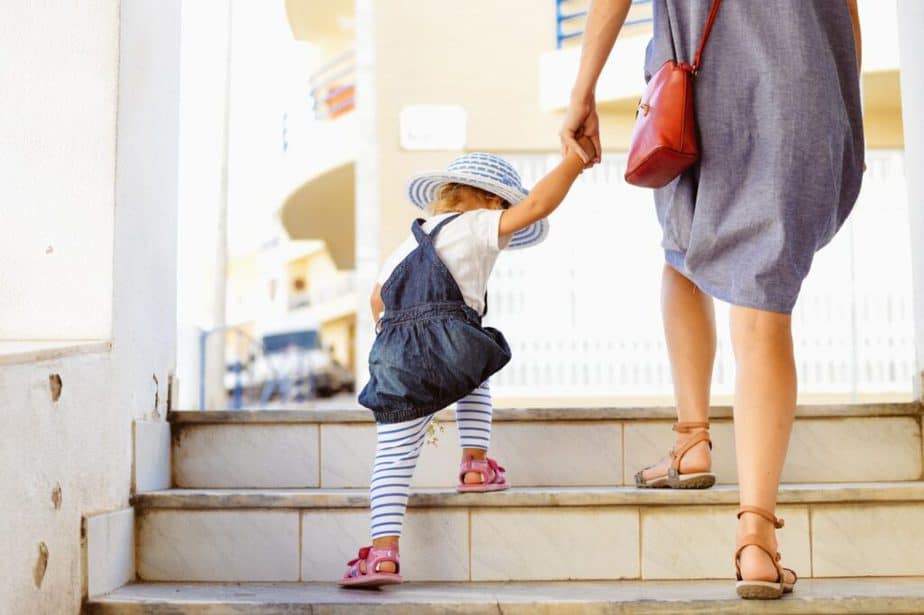 A young mom is walking upstairs with her baby