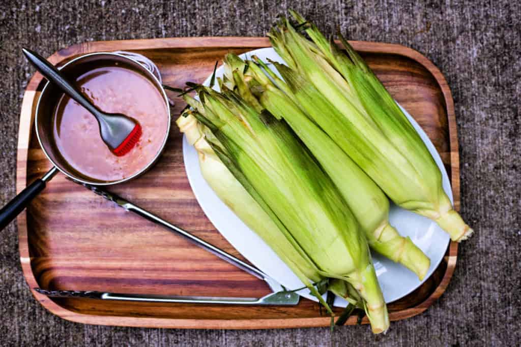 corn in the husks with spicy butter in a saucepan