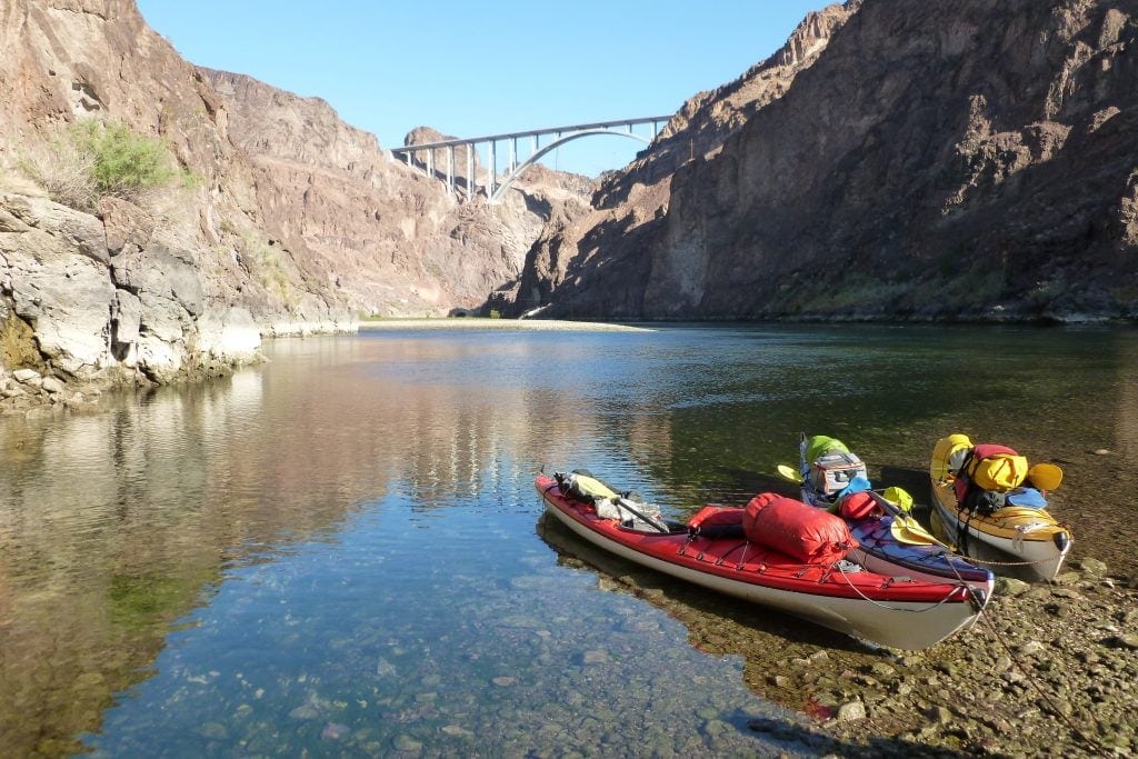 Flat water of the Colorado River below Hoover DAm. Kayaks pulled onto shore loaded for the Hoover Dam kayak tour.