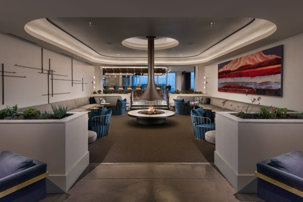 Modern, open hearth is center stage in this bar and dining space dressed in natural tones