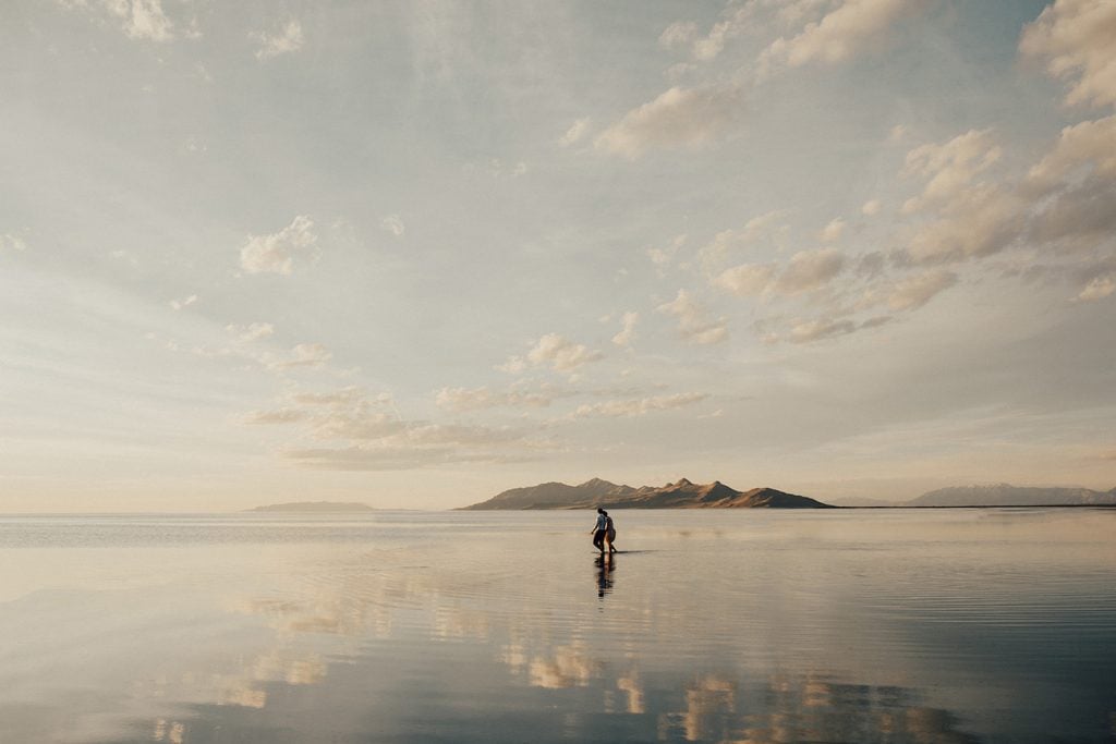Image of a couple holding hands while walking across the Bonneville Salt Flats, photographed by Alexa Ann Photography.