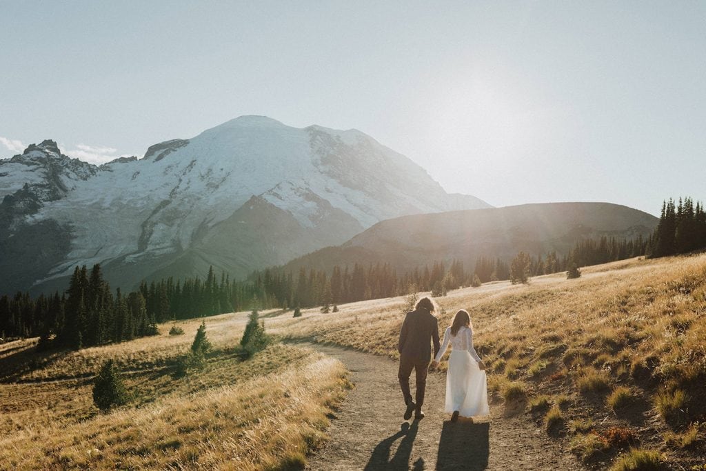 A newlywed couple holds hands while walking down a trail at a Washington National Park during golden of their Washington elopement
