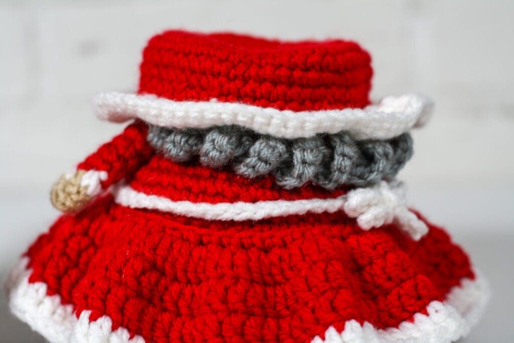The Crochet Mrs. Claus gnome is the perfect companion for the Santa gnome. Whip them both up in no time with this free crochet pattern.