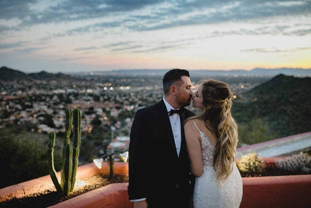 Different Pointe of View Tapatio Cliffs wedding with bride and groom kissing at sunset on mountain with Phoenix city lights below