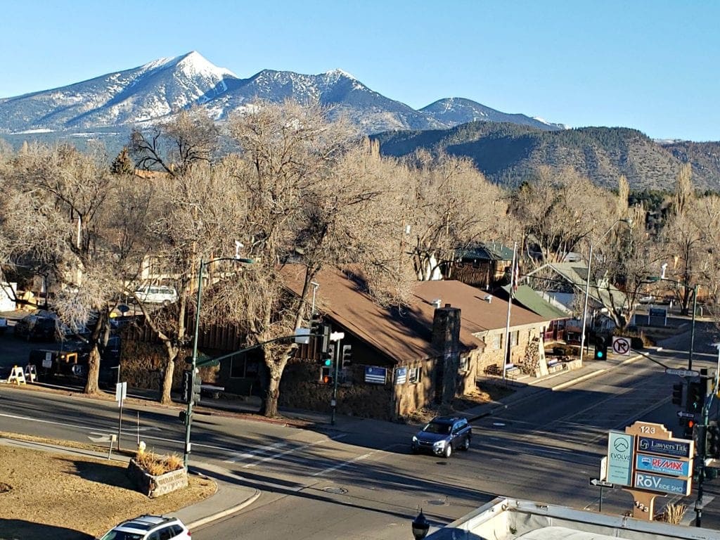Snow-topped SAn frnacisoc Peaks seen over tree tops in downtown Flagstaff